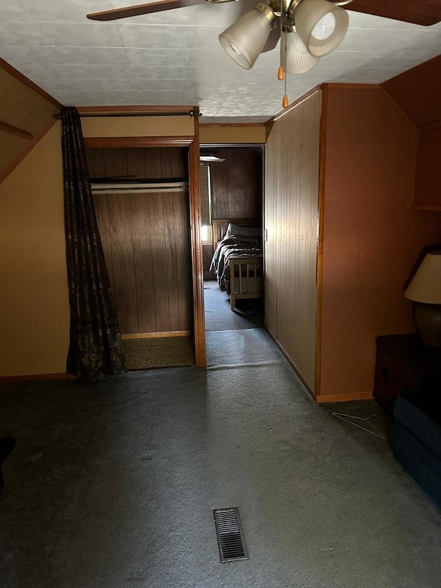 hallway featuring wooden walls, carpet, and lofted ceiling