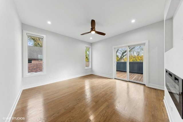 unfurnished living room with a wealth of natural light, light wood-type flooring, and ceiling fan