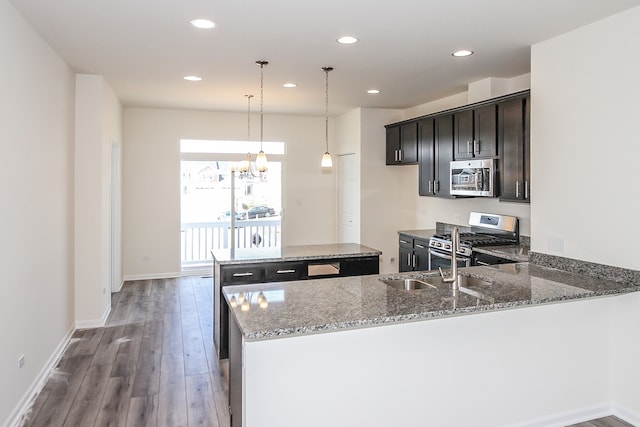 kitchen with light stone counters, kitchen peninsula, stainless steel appliances, an inviting chandelier, and dark hardwood / wood-style floors