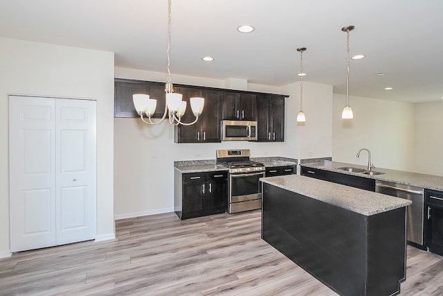 kitchen featuring appliances with stainless steel finishes, light hardwood / wood-style floors, sink, and pendant lighting