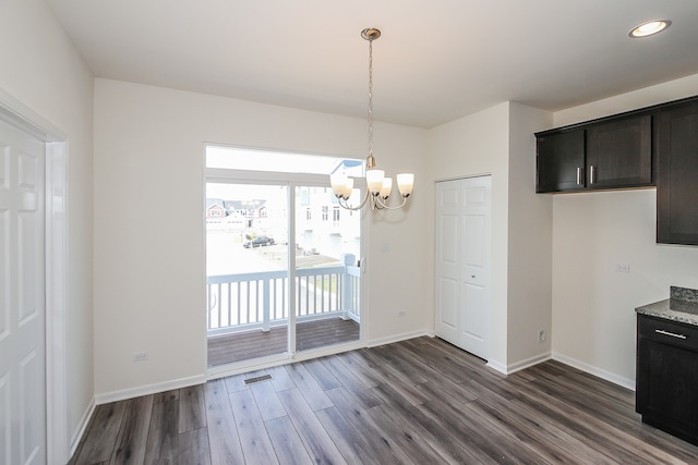 unfurnished dining area with dark hardwood / wood-style floors and a chandelier