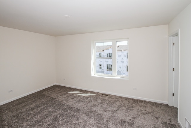 spare room with dark colored carpet