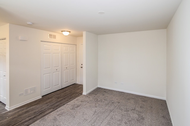 unfurnished bedroom featuring a closet and dark wood-type flooring