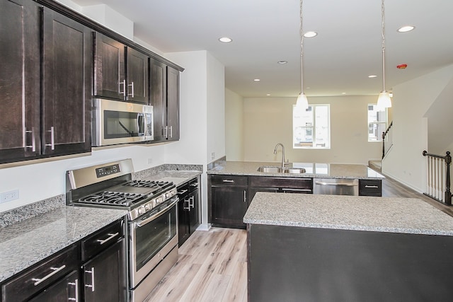 kitchen with appliances with stainless steel finishes, light hardwood / wood-style floors, a kitchen island, and sink