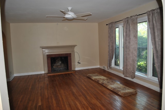 unfurnished living room featuring a brick fireplace, dark wood-type flooring, and ceiling fan