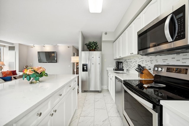 kitchen with tasteful backsplash, stainless steel appliances, sink, and white cabinets