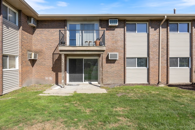 back of property featuring a balcony, a yard, and an AC wall unit