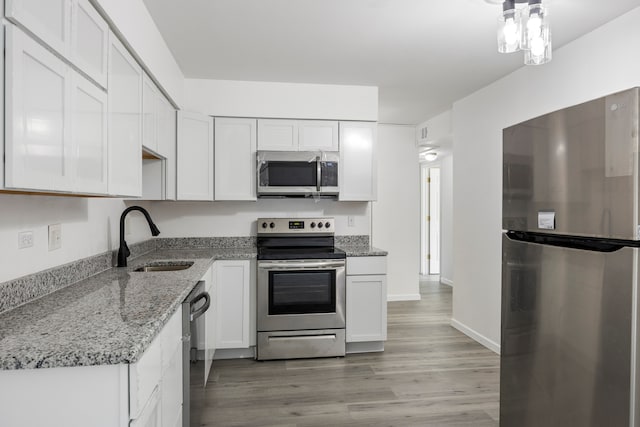 kitchen featuring light stone counters, light hardwood / wood-style floors, sink, white cabinetry, and appliances with stainless steel finishes