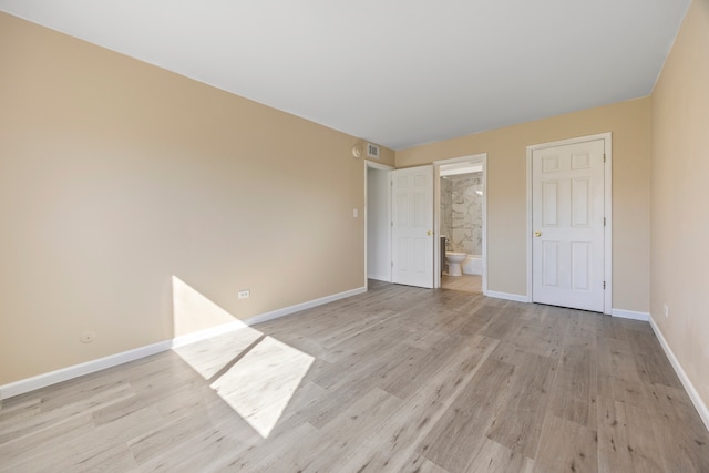 unfurnished bedroom featuring ensuite bath and light hardwood / wood-style floors