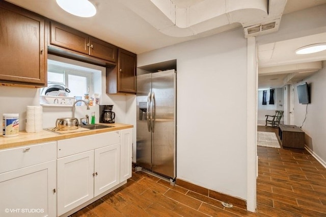 kitchen featuring stainless steel refrigerator with ice dispenser, sink, white cabinets, and butcher block counters