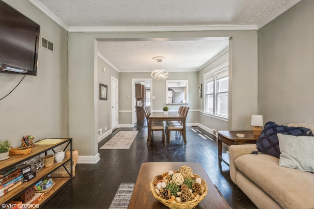 living room featuring an inviting chandelier, crown molding, dark wood-type flooring, and a textured ceiling