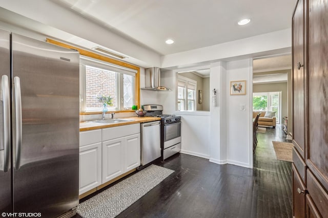 kitchen featuring sink, white cabinets, stainless steel appliances, dark wood-type flooring, and wall chimney range hood