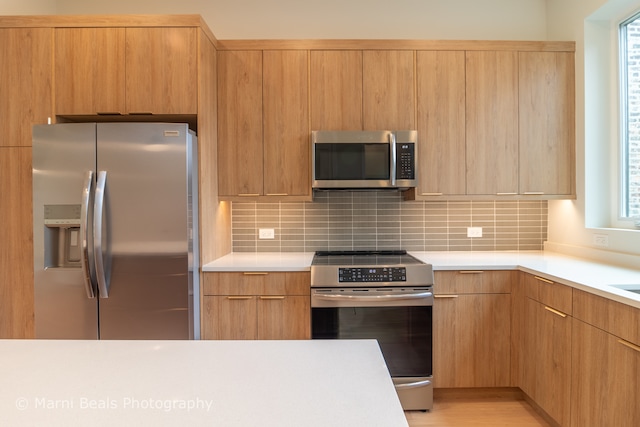 kitchen featuring appliances with stainless steel finishes, decorative backsplash, and a wealth of natural light