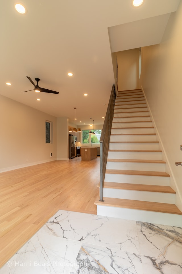 stairs with ceiling fan and hardwood / wood-style flooring