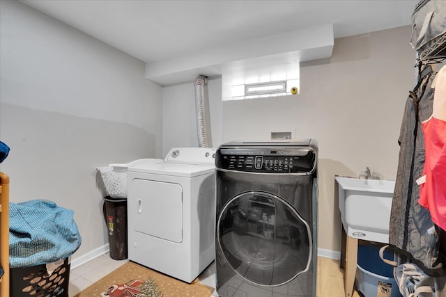 washroom featuring washing machine and dryer, sink, and light tile patterned floors