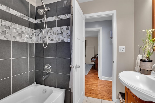 bathroom with wood-type flooring, tiled shower / bath combo, and vanity