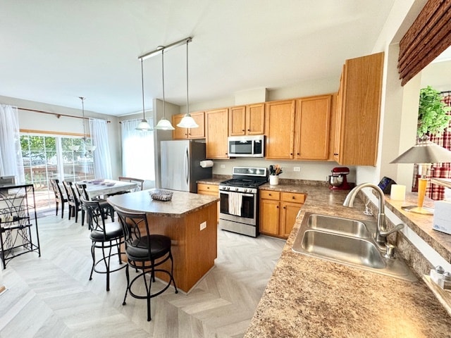 kitchen with pendant lighting, sink, stainless steel appliances, a center island, and a breakfast bar area