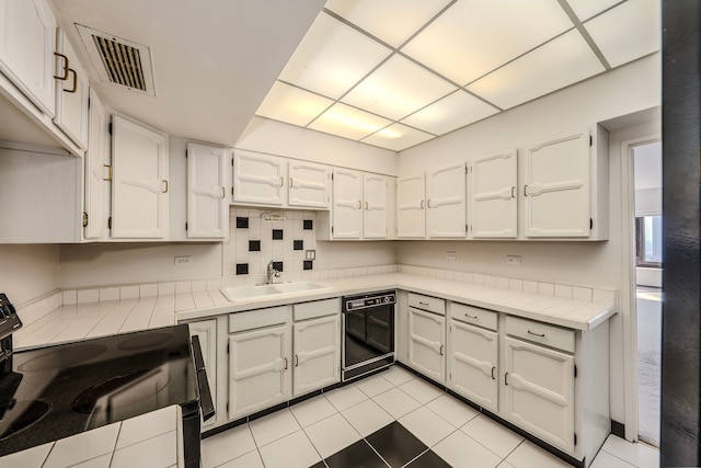 kitchen featuring sink, white cabinetry, electric stove, light tile patterned floors, and dishwasher