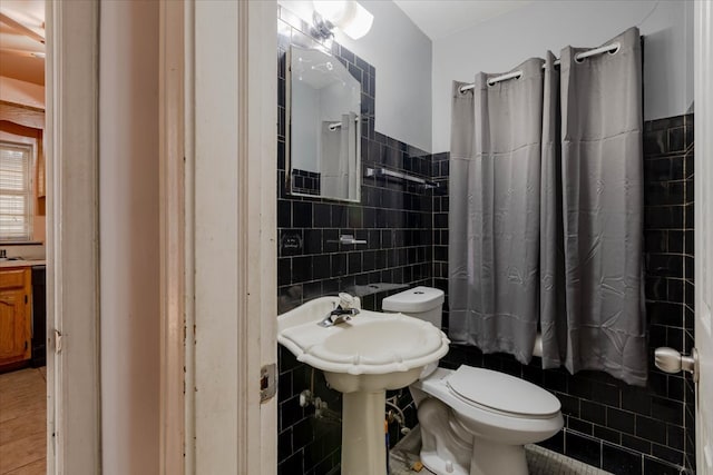 bathroom featuring tile walls, tile patterned flooring, and toilet