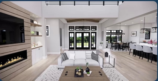 living room featuring a notable chandelier, a towering ceiling, a tile fireplace, and light hardwood / wood-style flooring