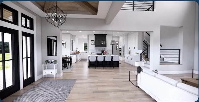 entryway with a notable chandelier, light wood-type flooring, a towering ceiling, and beam ceiling