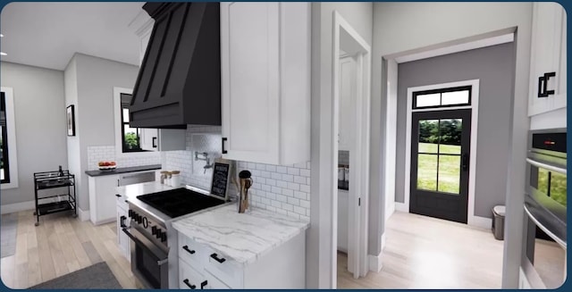 kitchen with light wood-type flooring, backsplash, white cabinetry, stainless steel appliances, and light stone countertops