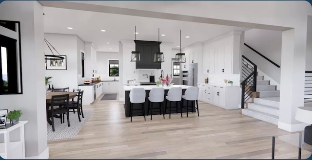 kitchen with white cabinets, tasteful backsplash, light hardwood / wood-style flooring, a center island, and a kitchen bar