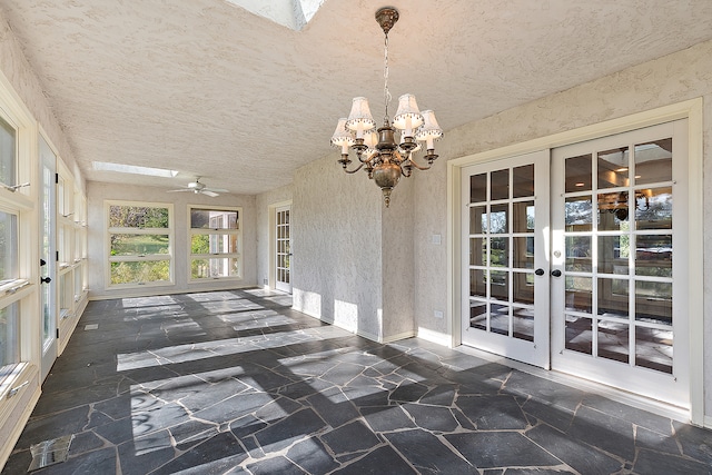 unfurnished sunroom featuring ceiling fan with notable chandelier and french doors