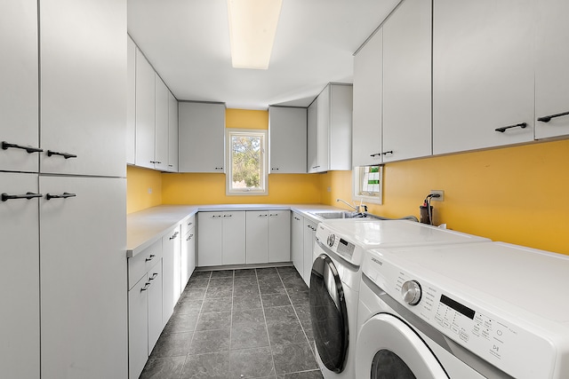 clothes washing area with sink, independent washer and dryer, dark tile patterned floors, and cabinets