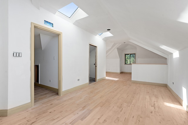 bonus room featuring light wood-type flooring and vaulted ceiling with skylight