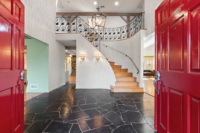 entryway with a high ceiling, a chandelier, and a textured ceiling