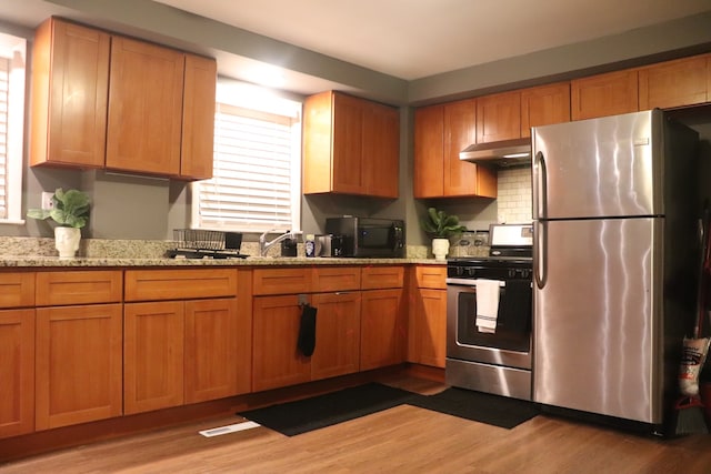 kitchen featuring light hardwood / wood-style flooring, stainless steel appliances, and light stone countertops