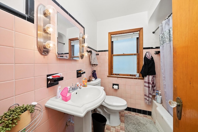 bathroom with tile walls, shower / bath combo with shower curtain, toilet, and tile patterned floors