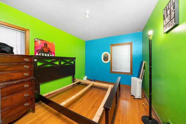 bedroom with light hardwood / wood-style floors and radiator heating unit