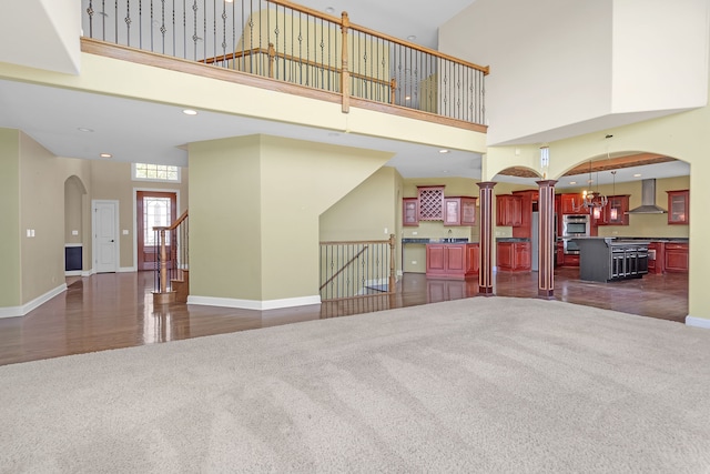 unfurnished living room with decorative columns, a high ceiling, and dark hardwood / wood-style flooring