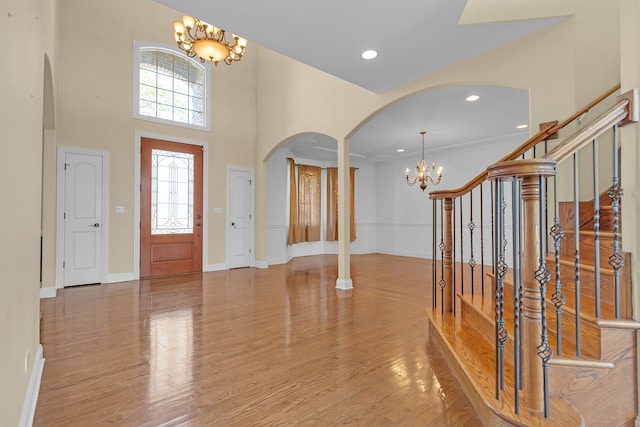 foyer entrance featuring ornamental molding, an inviting chandelier, light hardwood / wood-style floors, and a high ceiling