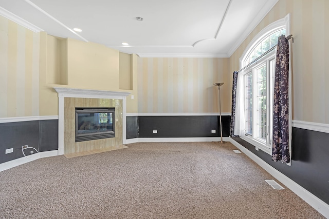 unfurnished living room with carpet floors, crown molding, a tiled fireplace, and a wealth of natural light