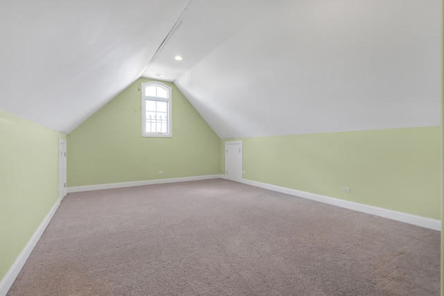 additional living space featuring light carpet and vaulted ceiling