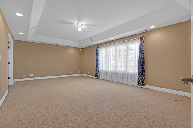 carpeted empty room with a raised ceiling and ceiling fan