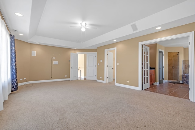 empty room with carpet floors, a raised ceiling, and ceiling fan