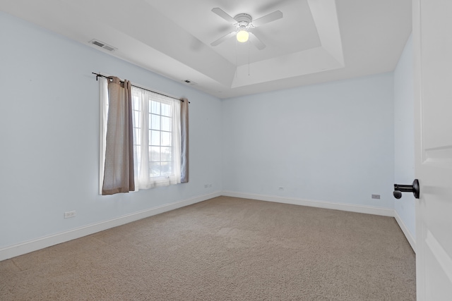 carpeted empty room with ceiling fan and a raised ceiling