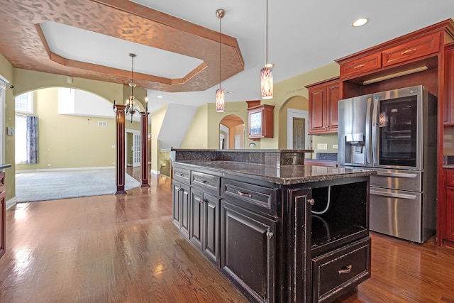 kitchen with hanging light fixtures, a tray ceiling, stainless steel fridge, and a center island