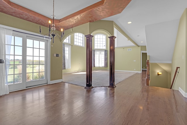 interior space featuring a notable chandelier, ornate columns, and hardwood / wood-style flooring