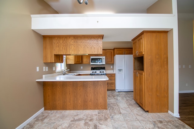 kitchen with white appliances, sink, and kitchen peninsula