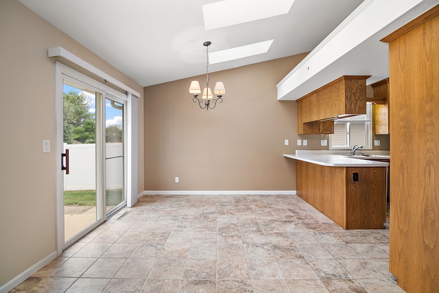 kitchen with hanging light fixtures, lofted ceiling with skylight, sink, and a chandelier