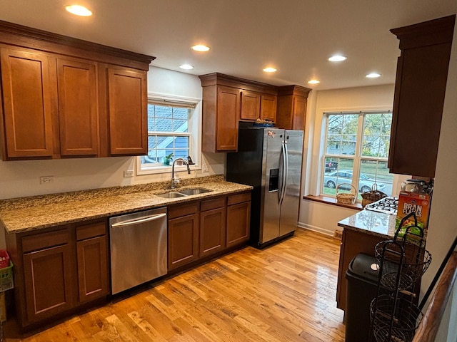 kitchen featuring stainless steel appliances, light hardwood / wood-style floors, a wealth of natural light, and sink