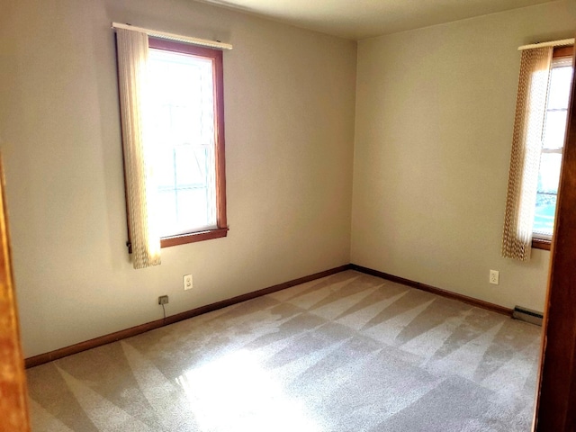 unfurnished room featuring carpet floors, a healthy amount of sunlight, and a baseboard heating unit