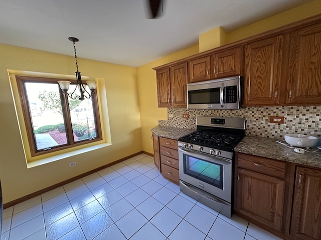 kitchen featuring dark stone counters, stainless steel appliances, backsplash, and a chandelier