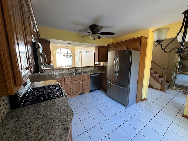 kitchen featuring ceiling fan with notable chandelier, appliances with stainless steel finishes, light tile patterned floors, and tasteful backsplash