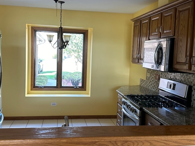 kitchen with dark brown cabinets, an inviting chandelier, appliances with stainless steel finishes, and backsplash